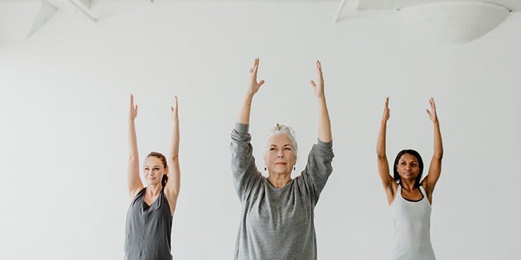 a group performing Urdhva Hastasana, also called Palm Tree Pose