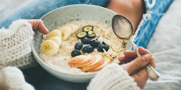 woman in jeans and sweater eating healthy oatmeal practicing mindful eating