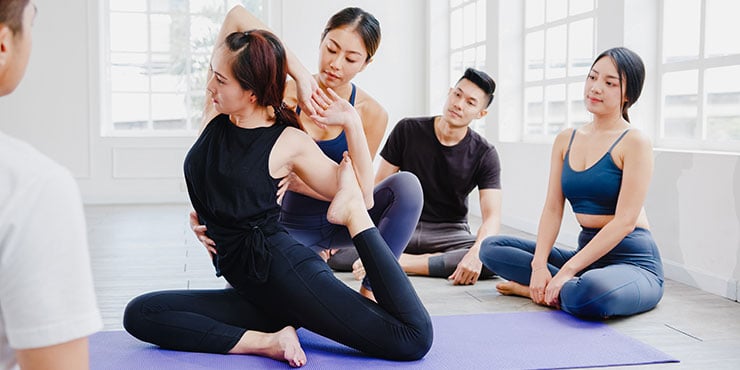 kvinde underviser yoga for en gruppe studerende